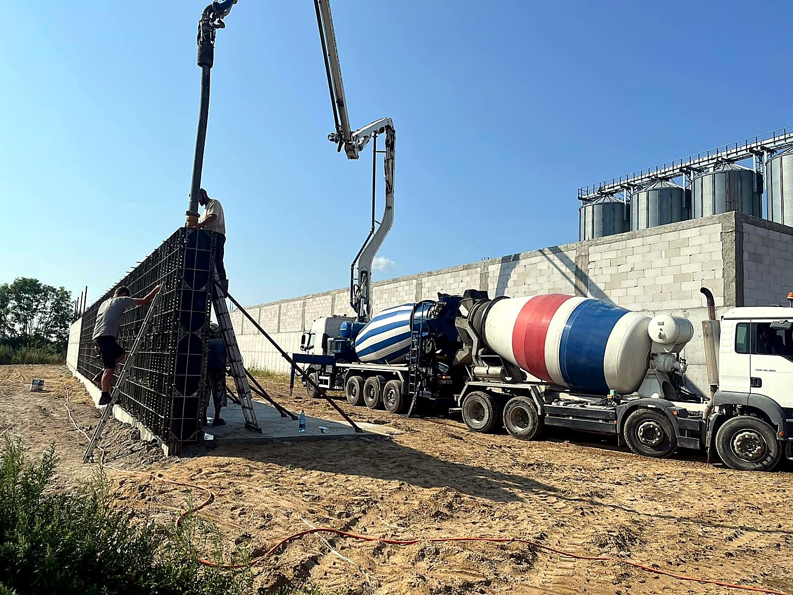 Pompa i dwie betonomieszarki przy betonowaniu ściany w szalunkach
