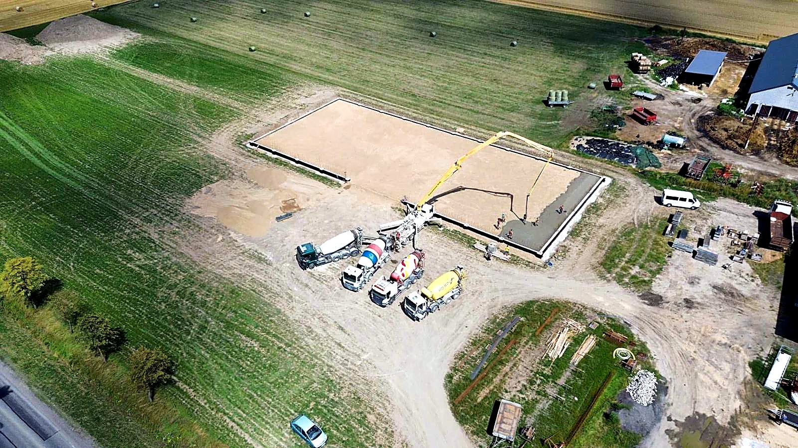 Kolejka betonomieszarek i pompa przy wylewce płyty fundamentowej z lotu ptaka