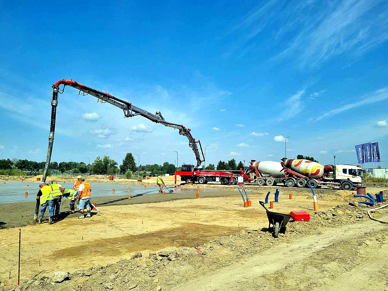 Ekipa rozprowadza świeży beton podawany pompą na dużej płycie