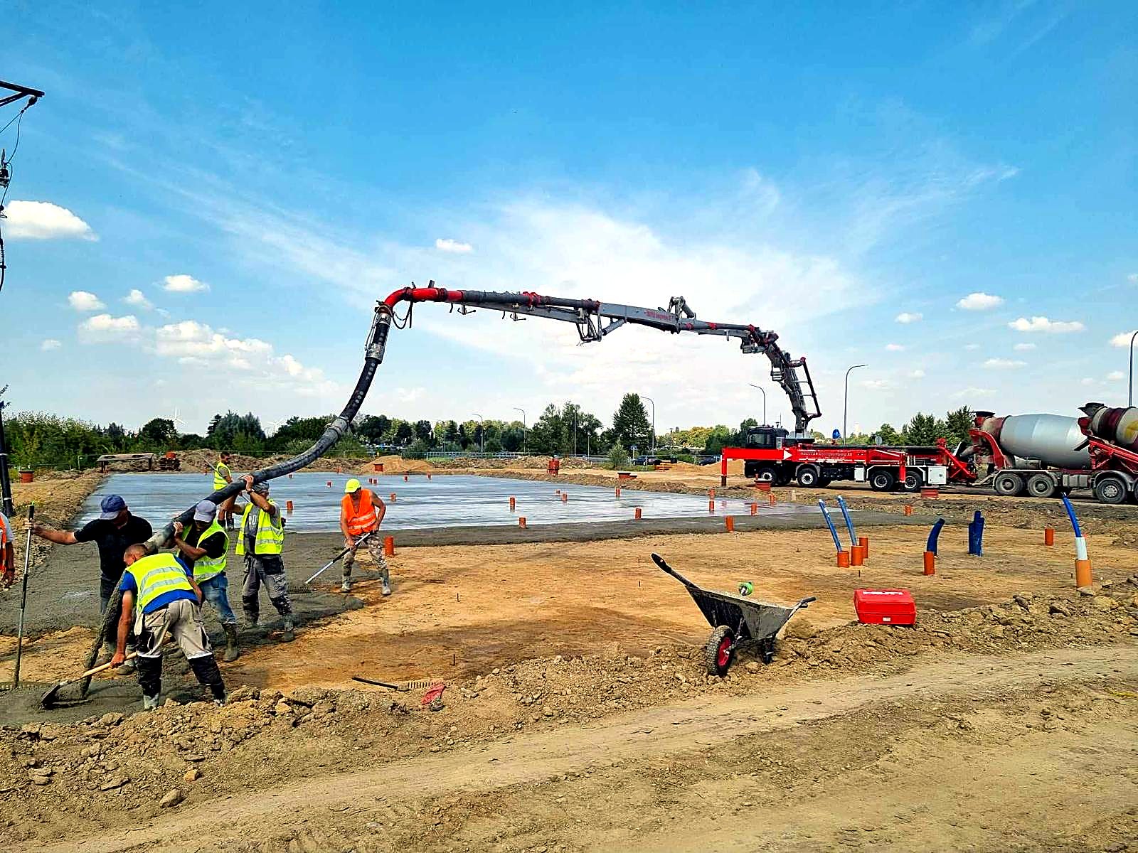 Ekipa rozprowadza świeży beton podawany wężem pompy na płycie