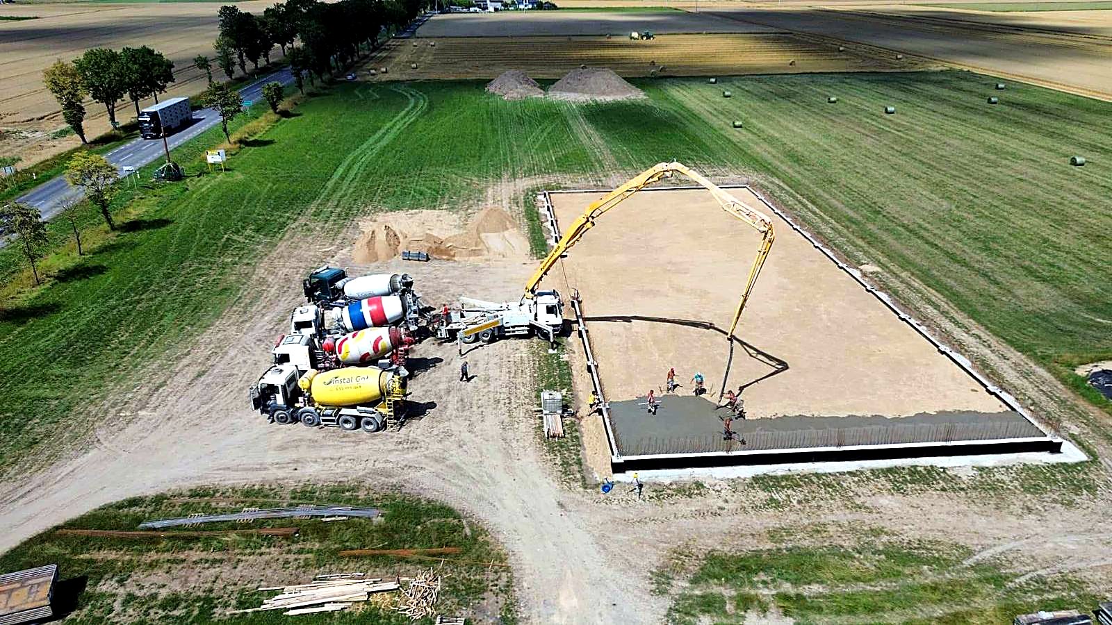 Betonowanie płyty fundamentowej z lotu ptaka, pompa i betonomieszarki