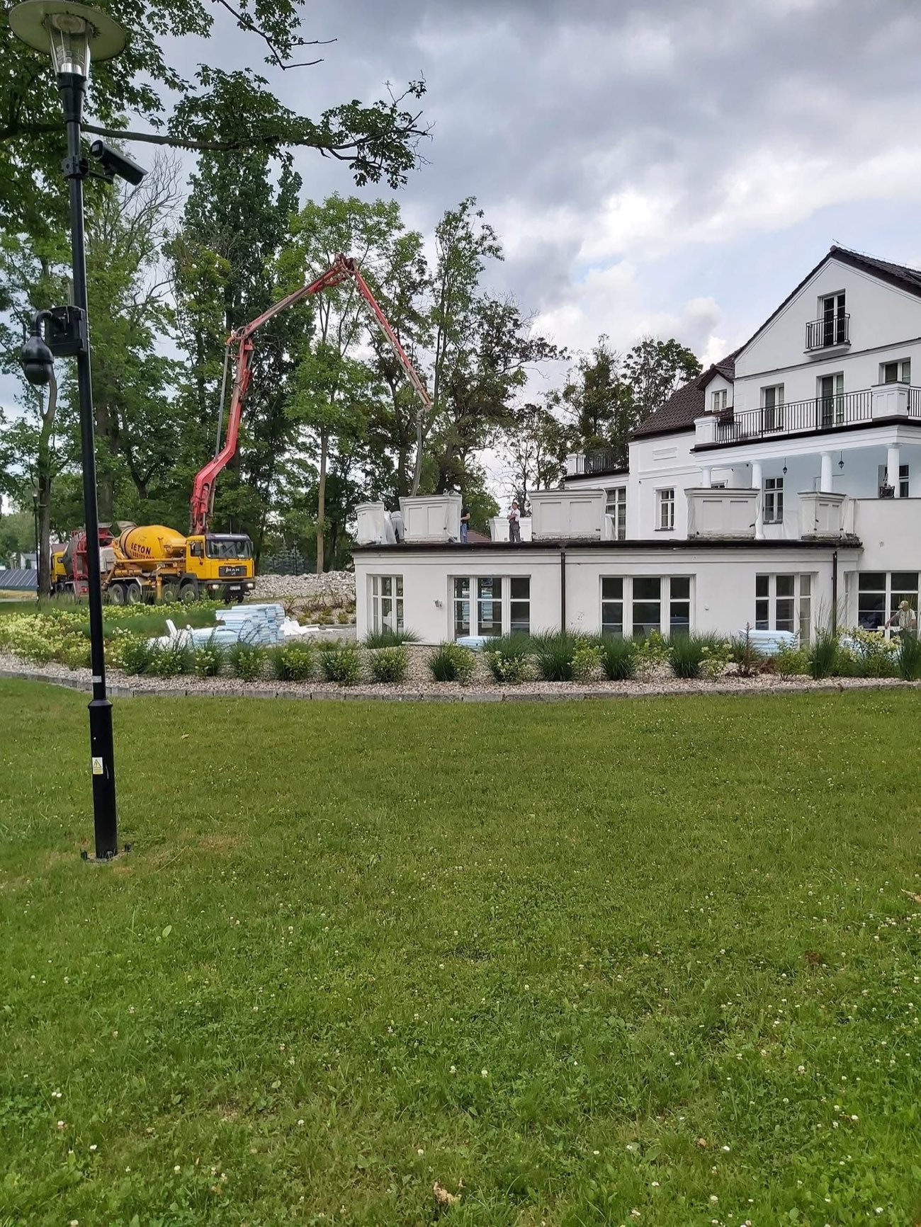 Rozbudowa obiektu w parku, beton podawany pompą ponad dachem budynku